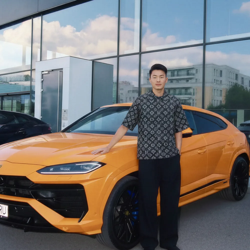 Man beside an orange Lamborghini Urus: sending BNB to KAST to spend stables
