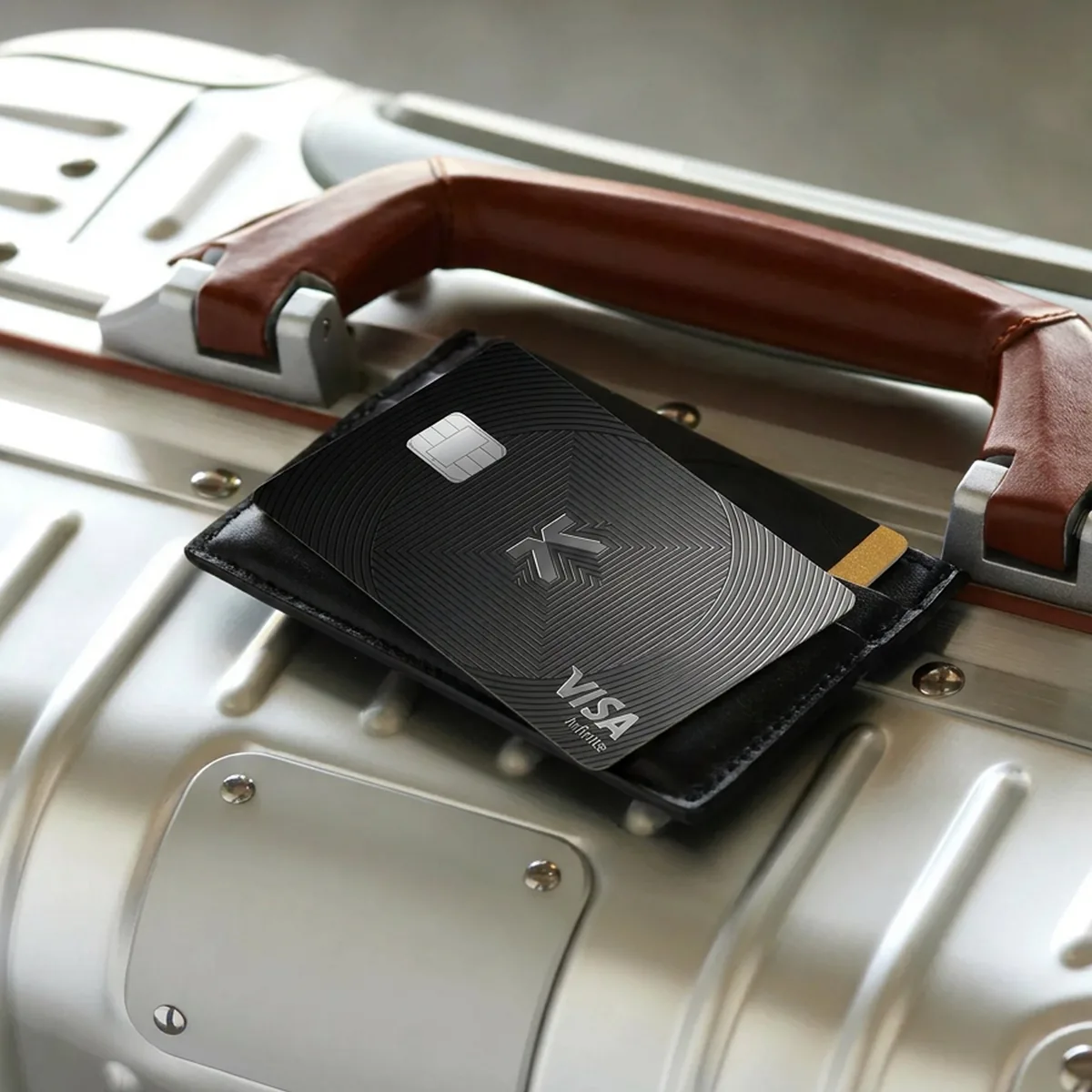 KAST Visa card in a leather sleeve on a silver suitcase, for paying abroad from the US
