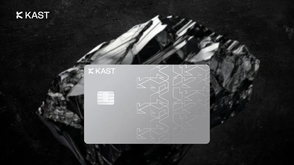 Silver KAST Visa card on a dark crystal background