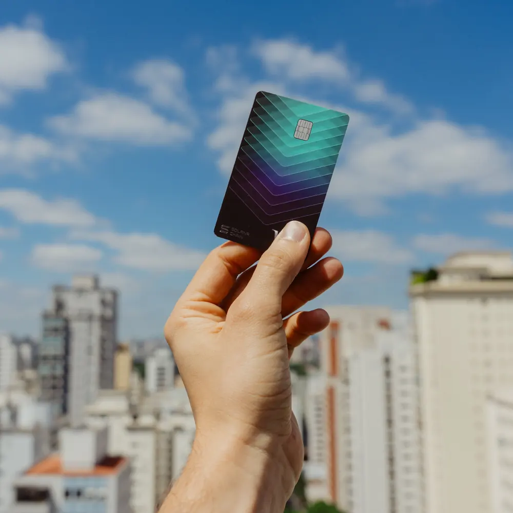 KAST Solana Card held up against a city skyline